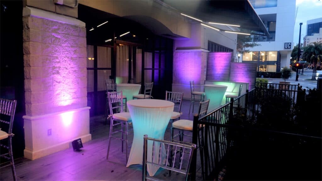 outdoor seating area with purple uplights and tables with chairs